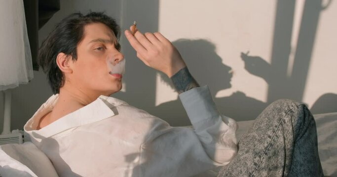 depressed nervous man is fed up everything , depression slow motion. Emotional guy with nicotine patch and cigarette in bedroom