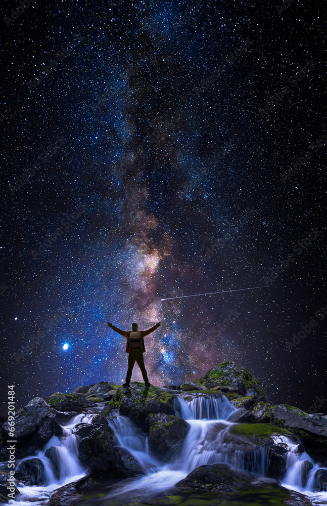 Wall mural man on top of a mountain with open arms in front of the universe