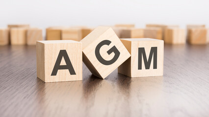 wooden cubes with text AGM on gray table