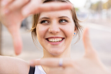 Smiling happy young woman gesturing frame with hands