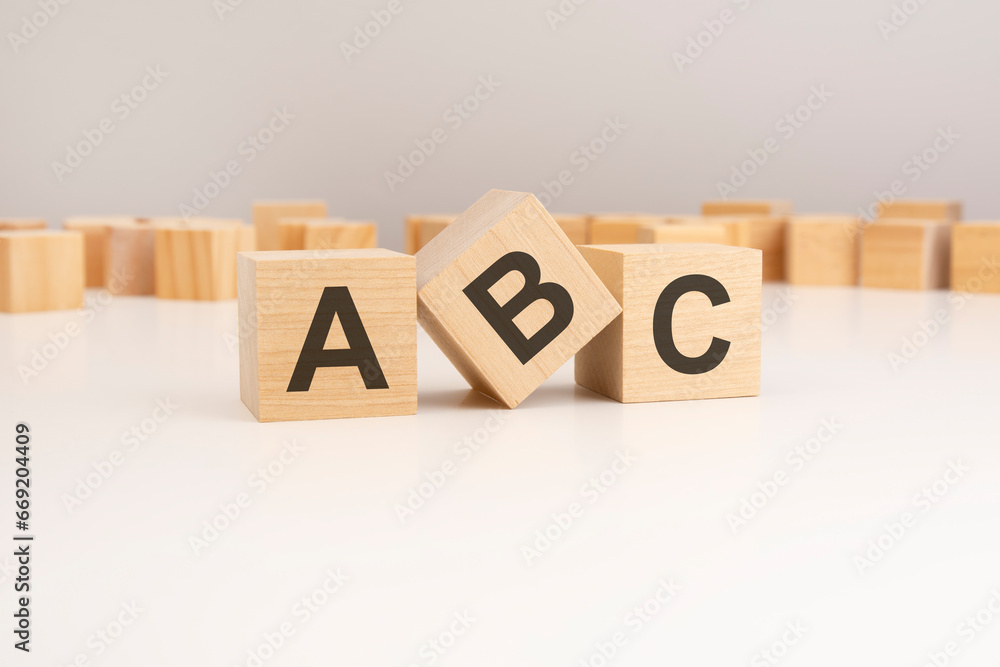 Poster three wooden cubes with abc symbols on them. white background. in the background there are many wood