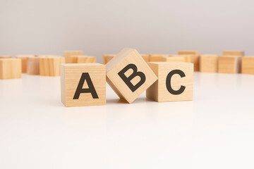 three wooden cubes with ABC symbols on them. white background. in the background there are many wooden blocks of different sizes