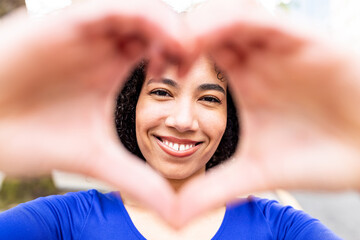 Happy young woman gesturing heart shape with hands