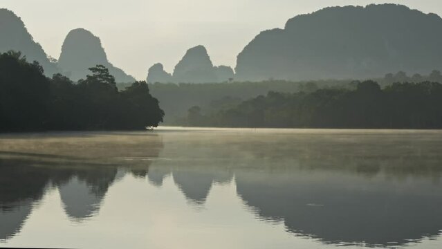 Reflection of the hills in the lake, covered morning fog, calm water landscape 