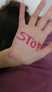 A woman holds her palm up to the camera with 'stop' written on it. Addressing gender violence, domestic abuse, and gender inequality. Empowerment, International Women's Day on March 8th. Equity, women
