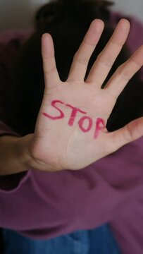 A woman holds her palm up to the camera with 'stop' written on it. Addressing gender violence, domestic abuse, and gender inequality. Empowerment, International Women's Day on March 8th. Equity, women