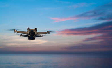 Naklejka premium small drone flying against a magnificent sunset seascape. 