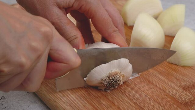 Peeling and cutting white garlic on a cutting board. Vegetable soup recipe. Ingredients close-up on the kitchen table
