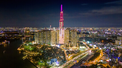Aerial sunset view at Landmark 81 - it is a super tall skyscraper and Saigon bridge with development buildings along Saigon river, cityscape in the night - obrazy, fototapety, plakaty