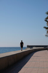 Muelle del puerto de Málaga, hombre andando por el muro del espigón, dia sin nubes, soleado....