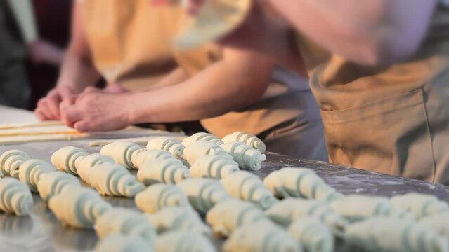 Female hands making croissants, shaping dough for bagels, twisting the dough with hands. Baking bread and bakery products, croissants, bagels. Close up.
