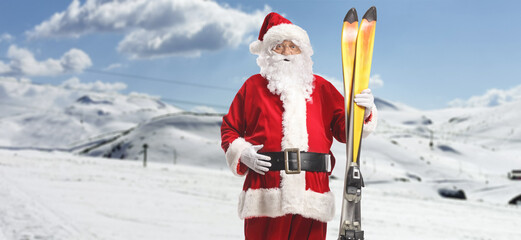 Santa Claus holding a pair of skis on a mountain