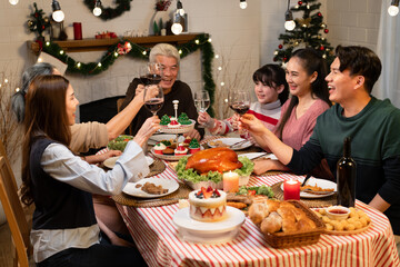 Three generation Asian family cheers with wine glass and celebrating Christmas in dinner at home	
