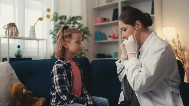 Woman pediatrician listening to girl's lungs with stethoscope, health check-up