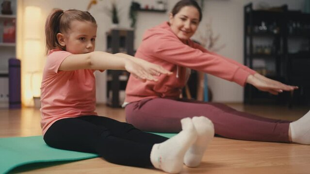Happy mom and little daughter doing fitness and stretching exercises at home