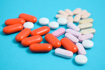 Colorful Medicine Pills in heart shape isolated on blue background, supplement, vitamin, colorful