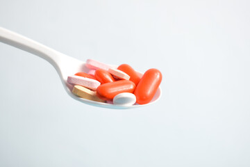 Colorful Medicine Pills in White spoon on white background, supplement, vitamin, colorful