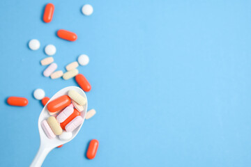 Colorful Medicine Pills in White spoon on blue background, supplement, vitamin, colorful