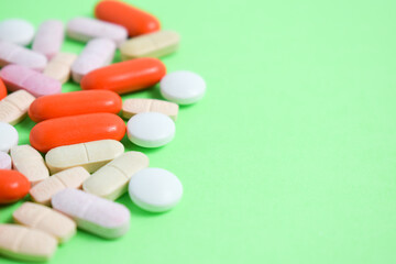 Obraz na płótnie Canvas colorful medical pills on green background with copy space, supplement, vitamin, colorful