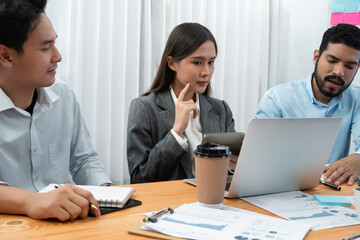 Multiracial analyst team use BI dashboard data to analyze financial report on meeting table. Group of diverse business people utilize data analysis by FIntech for success business marketing. Concord