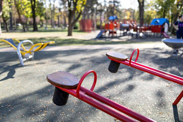 Red seesaws with play house in the background outdoors