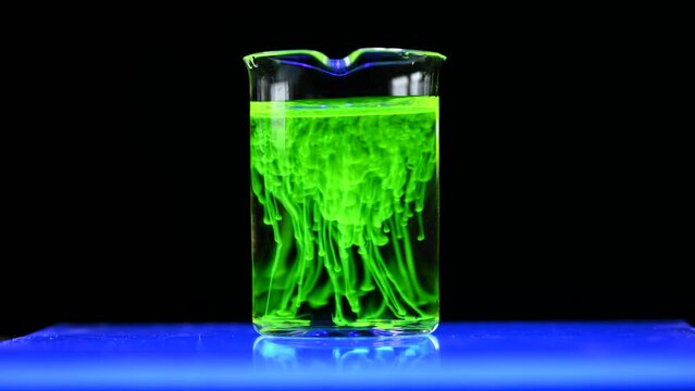 Fluorescent toxic chemical dissolving in the chemical solution. The scientist conducts demonstration experiments with solutions. The phenomenon of brownian motion fluorescence.