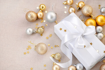 White present box, gold and silver Christmas, New Year decoration balls and confetti on neutral beige background. Festive aesthetic luxury banner for holiday business brand advertising, sale