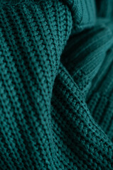Knitted green background. Close-up of a knitted blanket. Wavy folds material. Knitted warm green sweater or coat.
