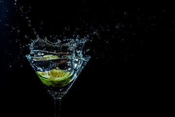 splash in a glass with lime slice on a black background
