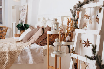 cozy New Year's decor of the room lit by the magic garland lights. Festive atmosphere before holidays. Scandinavian style. Loft interior with bed with white and grey cushions and wooden shelves