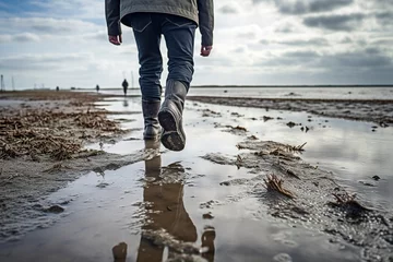 Fototapeten man walking in rubber boots in the Wadden Sea © Jorge Ferreiro