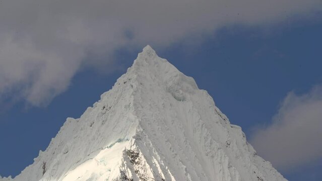 ice covered glacier of a pyramid shaped mountain at laguna paron lagoon in the high andes mountains of the cordillera blanca at huascaran, Peru, with snow covered mountain peaks on a bright sunny day.