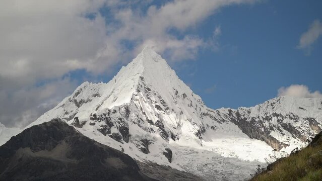 ice covered glacier of a pyramid shaped mountain at laguna paron lagoon in the high andes mountains of the cordillera blanca at huascaran, Peru, with snow covered mountain peaks on a bright sunny day.