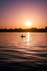 Lonely fisherman on a boat on the river at sunset