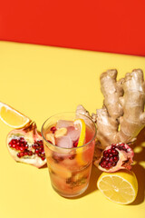 Glass of tasty pomegranate cocktail with lemon and ginger root on color background