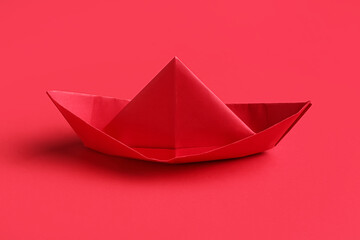 Origami boat on red background
