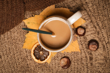Cozy winter lifestyle concept. Cup of hot drink with warm knitted clothes.