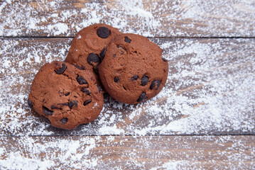 Shortbread cookies with chocolate chips on wooden background sprinkled with powdered sugar. Fresh pastry. Oatmeal cookies for Breakfast.