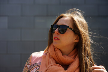 Portrait of mid 30 business woman with brown hair with black sunglasses smiling and gray background.