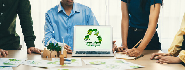 Recycle sign displayed on green business laptop while business team presenting green design to...