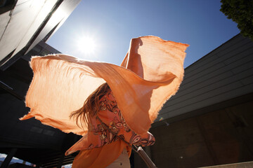 Successful positive woman in orange fashion clothes waving orange scarf in business building...