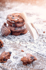 Cookies with chocolate slices sprinkled with powdered sugar and a wooden measuring spoon. Fresh pastry on wooden background.