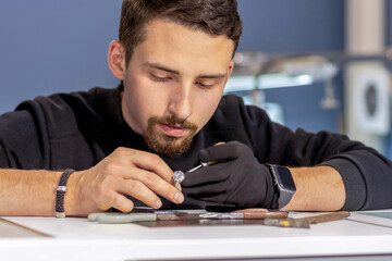 The jeweler is working on a ring with zircons.