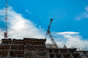 Construction cranes work on creation site against blue sky background