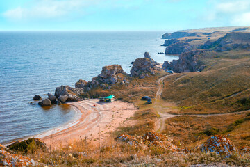 Sea bay with a sandy beach and tourist camping on the shore. Sea picturesque autumn landscape