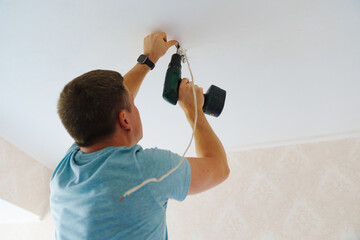 A man is working on the installation of a ceiling luminaire on the ceiling.