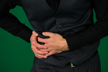 emotions of a handsome man guy on a green background chromakey close-up pain in the right side hands holding the side a man in a suit. chroma key medicine treatment care proper nutrition