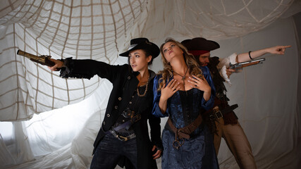 Daring pirates are shooting in all directions, a young woman and a cheerful guy in pirate costumes