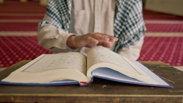 Islamic prayer concept Muslim man carefully studies the Holy Quran and prays to Allah in the mosque