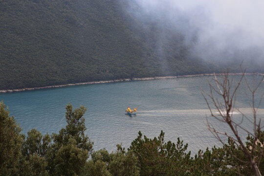 Firefighting airplane collecting water from sea. Forest burning 